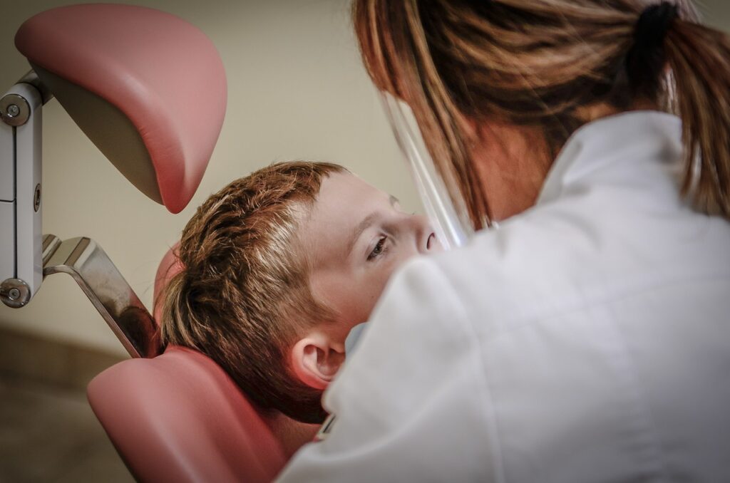 Dentiste examinant un jeune garçon sur un fauteuil dentaire lors d’un contrôle
